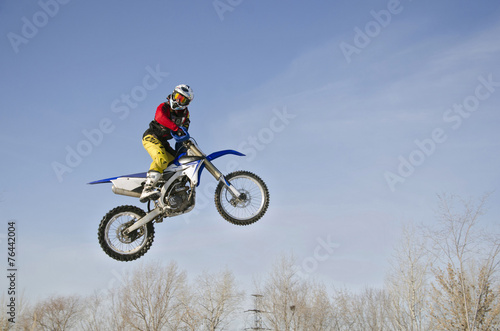 High in the air MX racer on a motorcycle, on a background cloudy