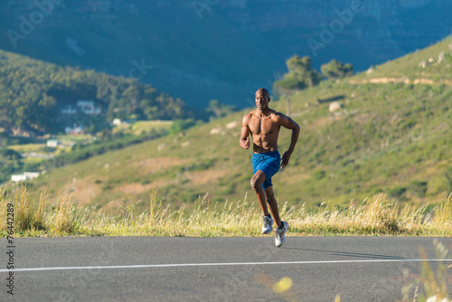 Athletic, black male running along a road