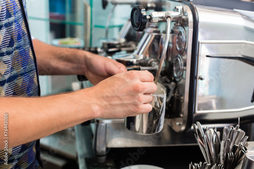 Bartender in Cafe Bar sch  umt Milch auf