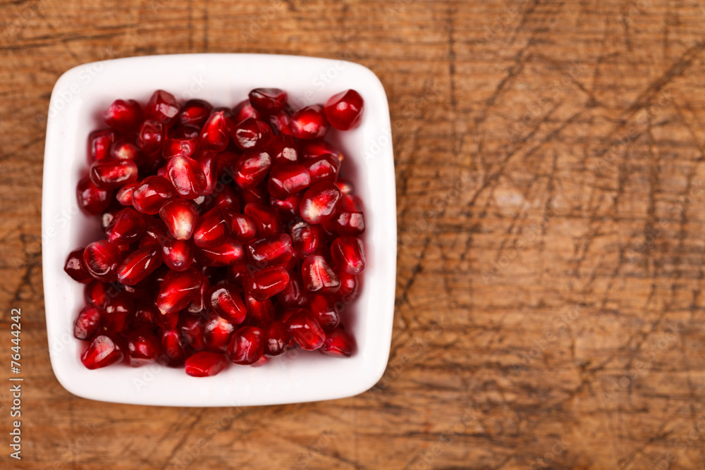 Red grenadine seeds on white plate Red grenadine seeds on white plate
