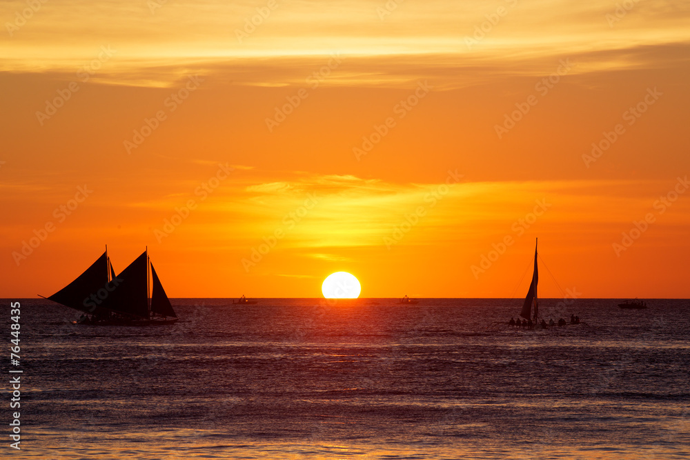 Fototapeta premium Sailboats at sunset on a tropical sea. Silhouette photo.