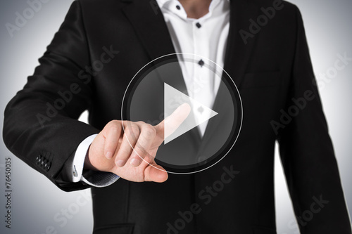 Business man in suit pressing on virtual play button.