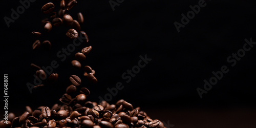 Fotografija High contrast image of coffee beans being dropped onto pile with