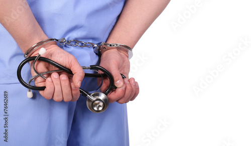 Doctor with stethoscope in handcuffs isolated on white photo