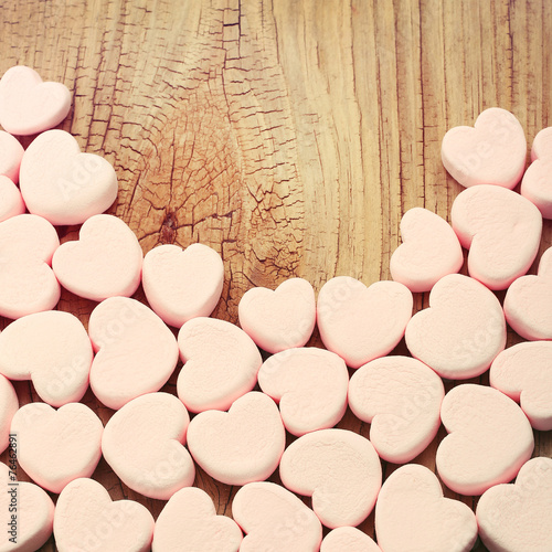 Heart marshmallows over wooden background