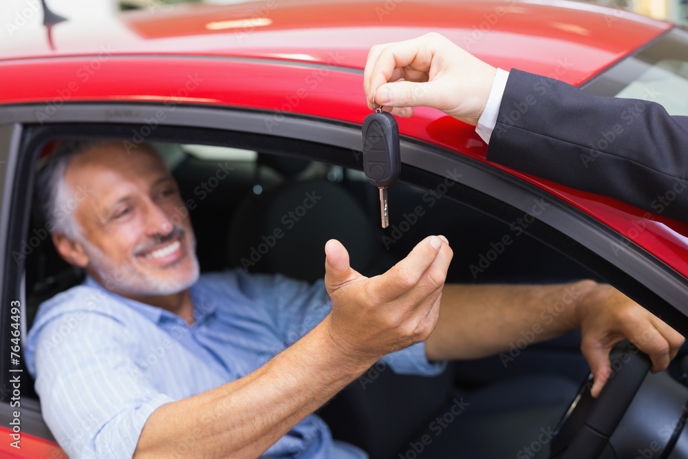 Smiling man driving a car while salesman his giving key Smiling man driving a car while salesman his giving key