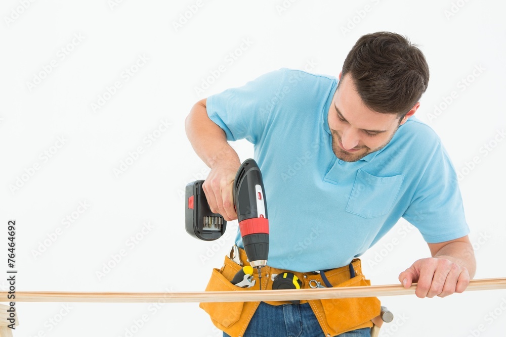Construction worker using hand drill on wooden plank Construction worker using hand drill on wooden plank