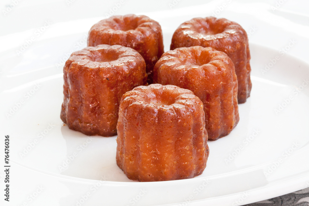Canelés de Bordeaux sur assiette blanche Canelés de Bordeaux sur assiette blanche