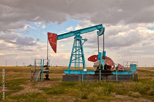 Oil pump in the field on a background cloudy sky