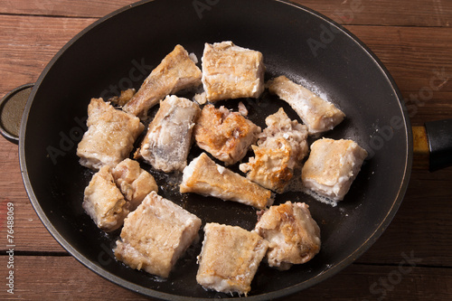 Some pieces of fried fish filet in a frying pan