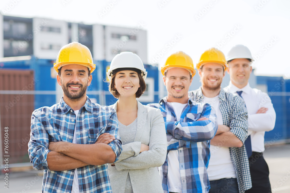 group of smiling builders in hardhats outdoors group of smiling builders in hardhats outdoors