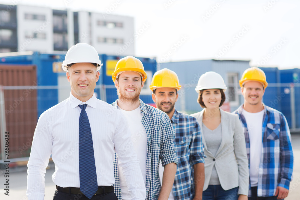 group of smiling builders in hardhats outdoors group of smiling builders in hardhats outdoors