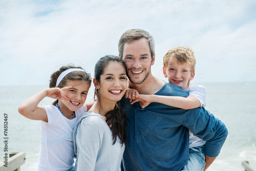 happy couple carrying their children on their backs on the beach happy couple carrying their children on their backs on the beach
