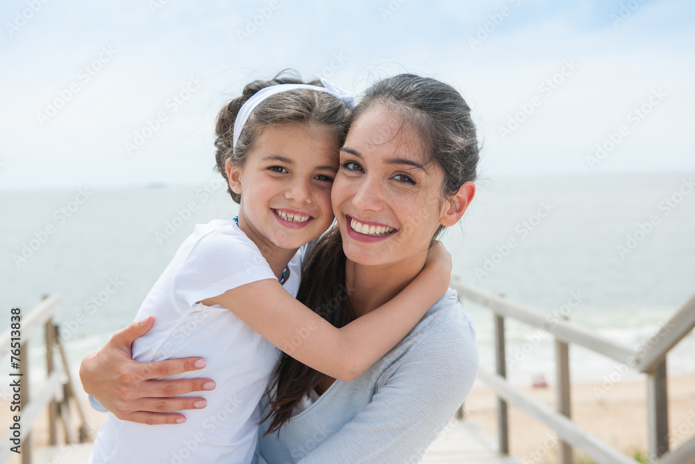 beautiful mom and her daugther at seaside smiling at camera