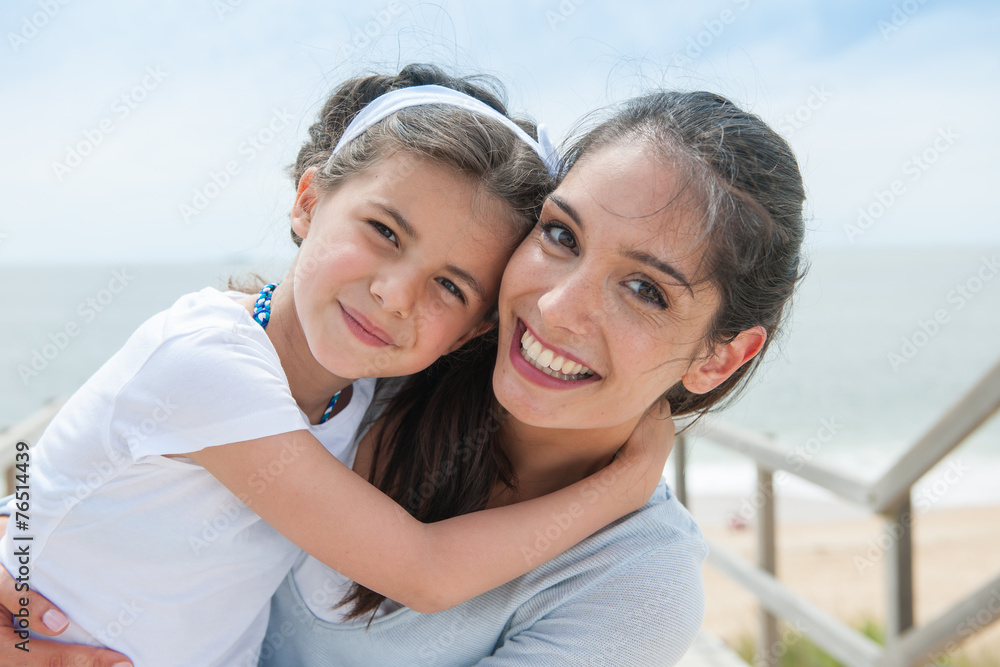 beautiful mom and her daugther at seaside smiling at camera