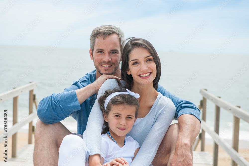  happy family sitting on a wooden pontoon in front of the sea