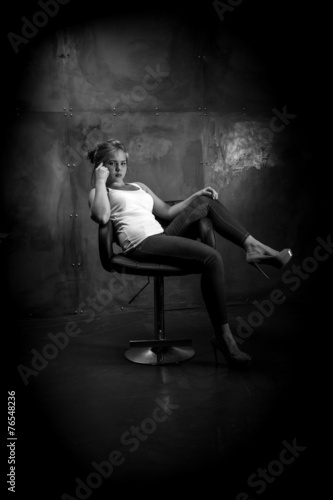 Monochrome photo of sexy woman sitting on chair at grungy room