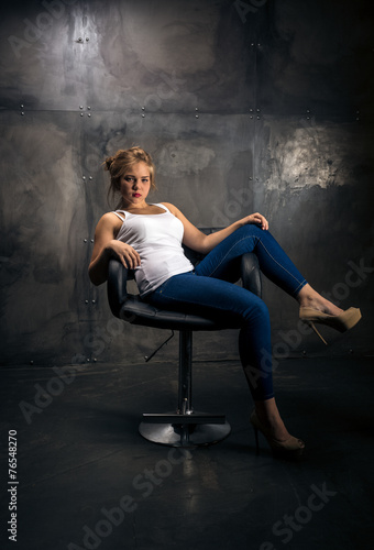 seductive woman sitting on chair at dark grungy room