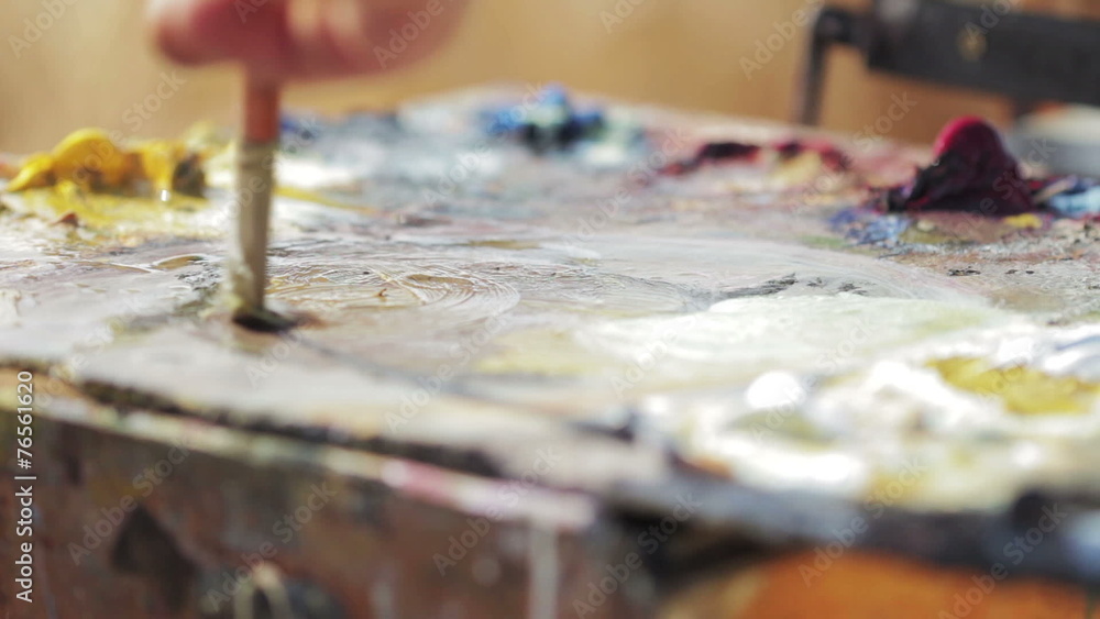 painter mixes with the brush colors in his palette painter mixes with the brush colors in his palette