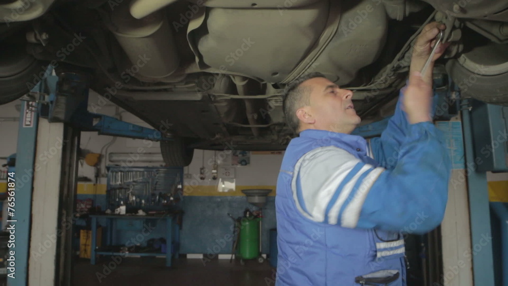 Auto mechanic repairing a car ( under a car lifts) with wrench- dolly Auto mechanic repairing a car ( under a car lifts) with wrench- dolly