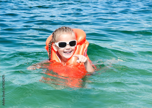 Smiling little girl swimming with life jacket