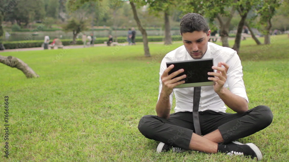 Business man sitting beneath the tree using tablet Business man sitting beneath the tree using tablet