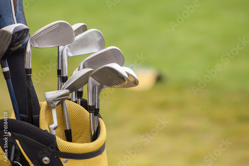 set of golf clubs over green field background photo