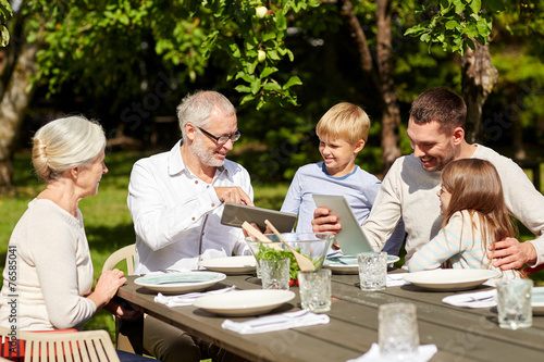 happy family with tablet pc at table in garden