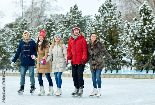 happy friends ice skating on rink outdoors