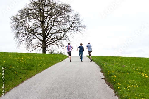Drei junge Männer rennen einen Berg rauf