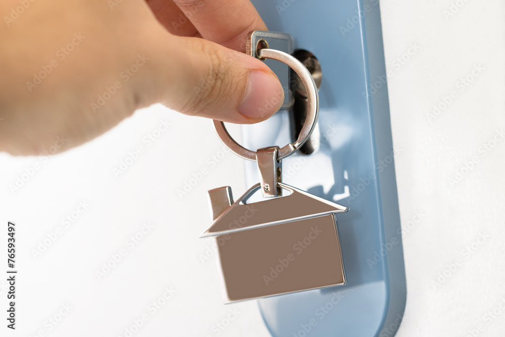 Obraz premium Finger Inserting Key In Keyhole