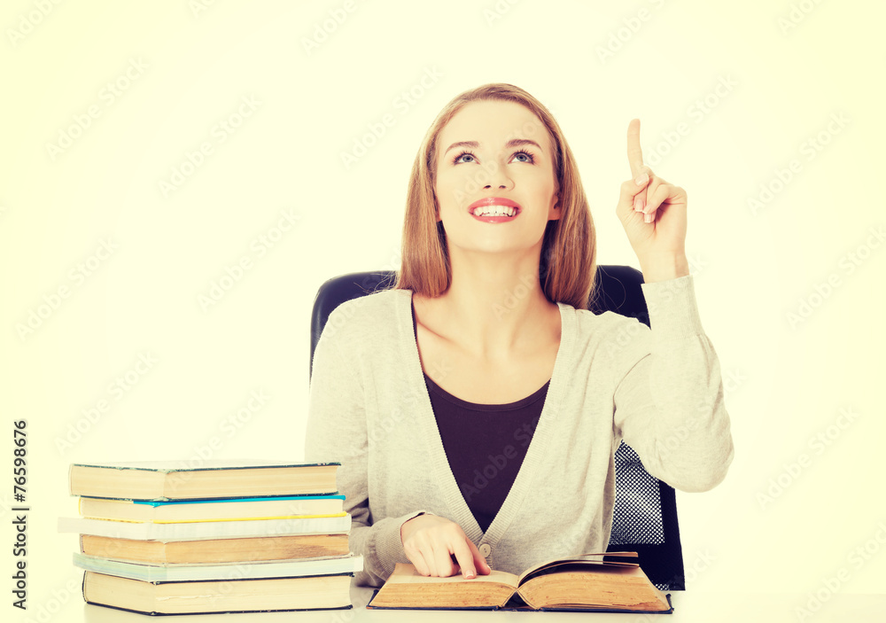 Woman sitting by stack of books and pointing up. Woman sitting by stack of books and pointing up.