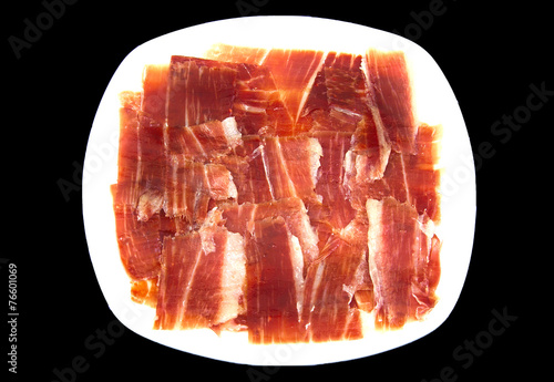 Plate of spanish serrano ham on black background. photo