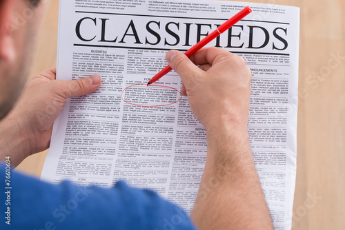 Man Highlighting Advertisement On Newspaper