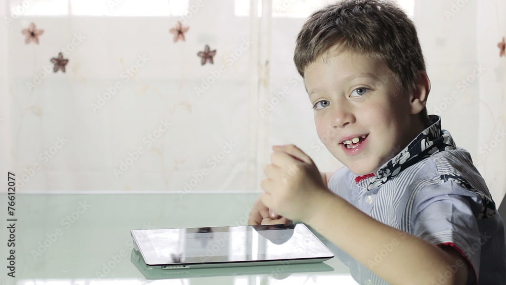 beautiful child uses a tablet and looks at the camera beautiful child uses a tablet and looks at the camera