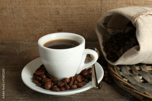 Cup of coffee with beans on rustic wooden background