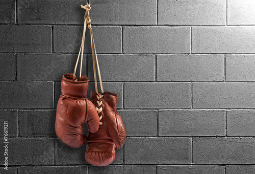 Pair of vintage boxing gloves hanging on a wall © photology1971