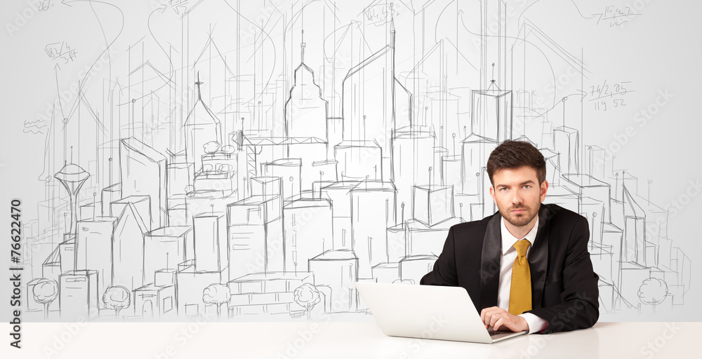 Businessman sitting at the white table with hand drawn buildings Businessman sitting at the white table with hand drawn buildings