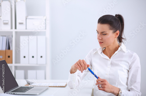 Attractive businesswoman sitting on a desk with laptop in the