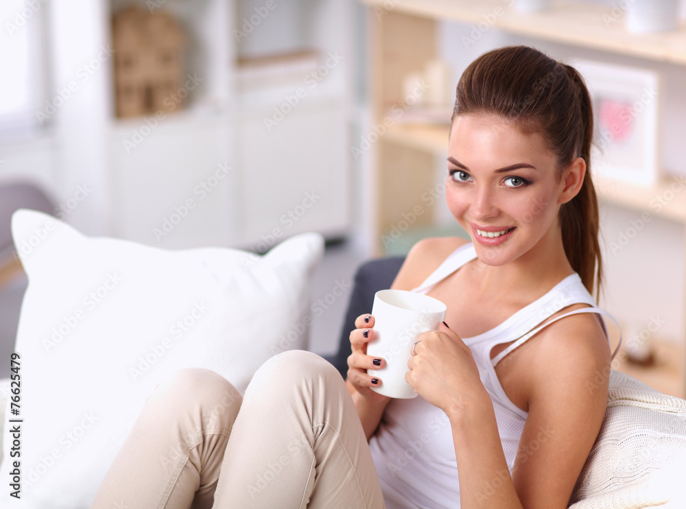 Young beautiful woman with a cup on sofa at home Young beautiful woman with a cup on sofa at home