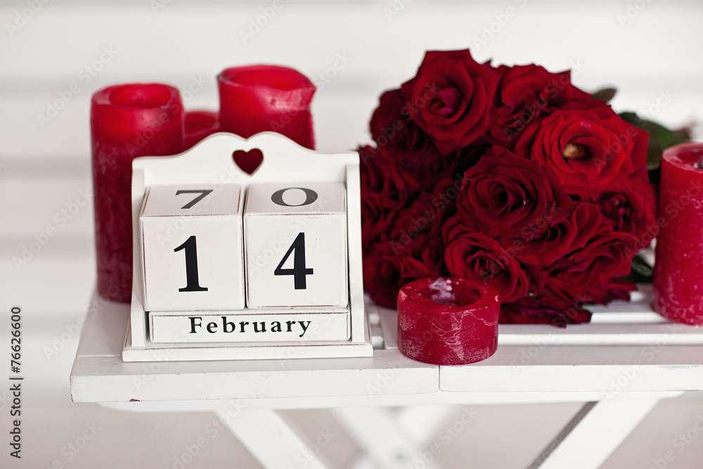 Fototapeta premium red roses lay on the table near calendar with the date of Febru