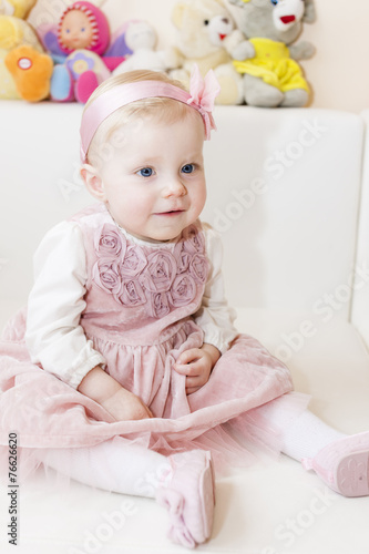 portrait of sitting toddler girl wearing pink dress