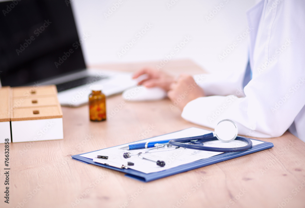 Female doctor sitting on the desk and working a laptop in Female doctor sitting on the desk and working a laptop in