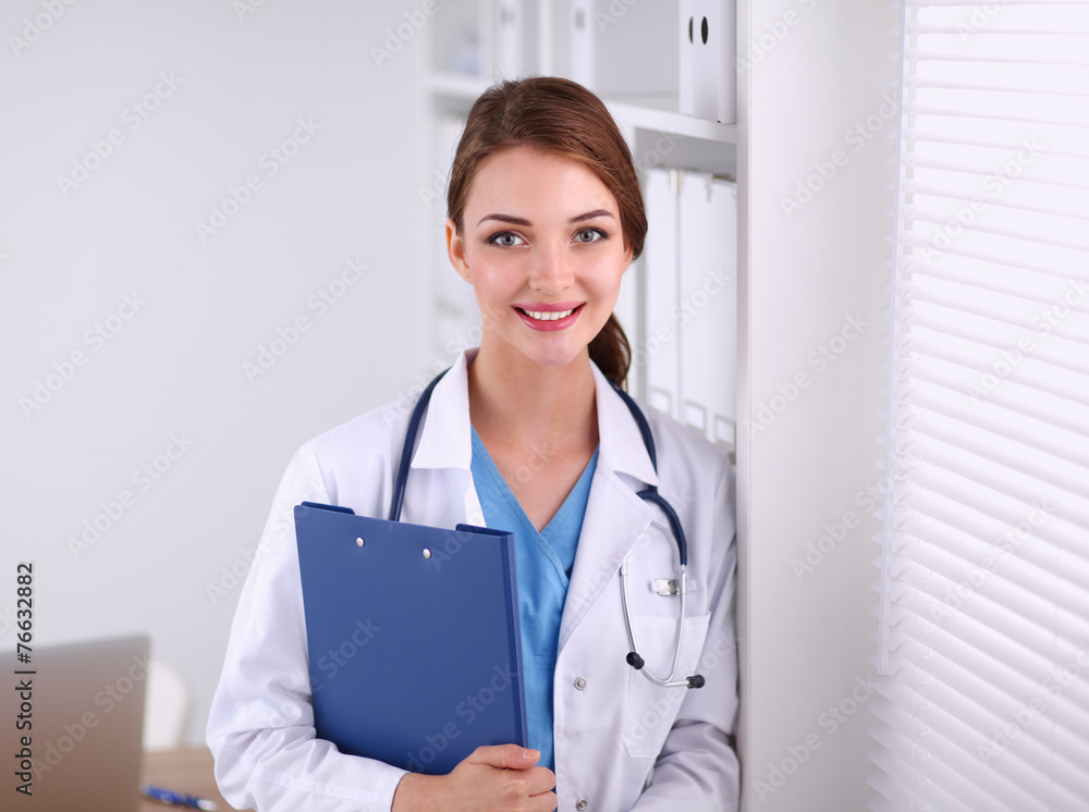 Smiling female doctor with a folder in uniform standing at Smiling female doctor with a folder in uniform standing at
