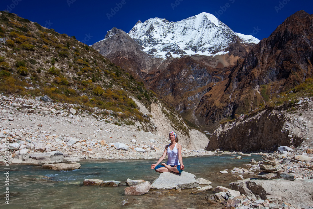 Fototapeta premium Young woman is practicing yoga at mountain lake