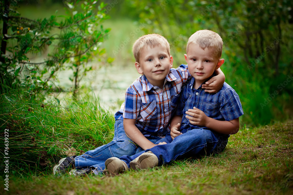 Two brothers hugging each other outdoor, smiling and laughing Two brothers hugging each other outdoor, smiling and laughing