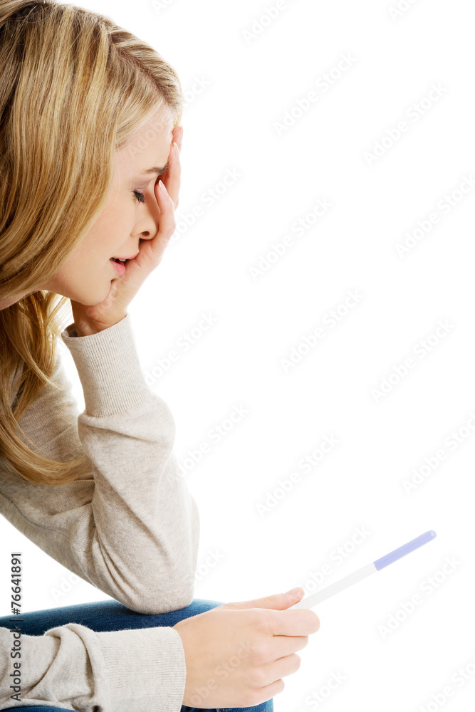 Sad young woman holding pregnancy test Sad young woman holding pregnancy test