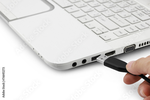 Hand connecting USB cable to laptop computer on white background