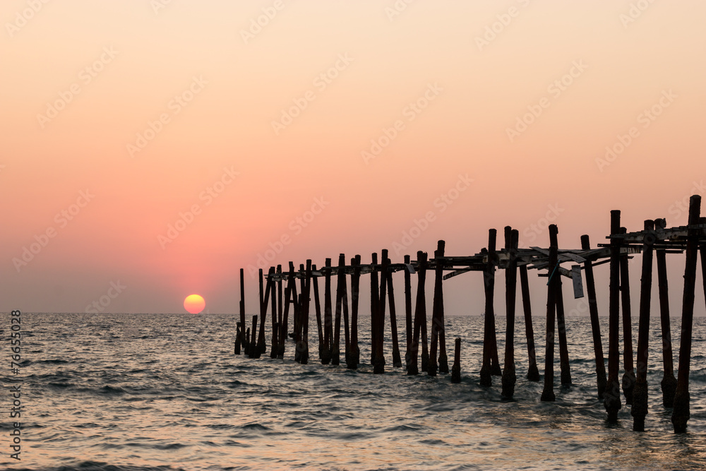 Decaying wooden bridge in the sea with sunset