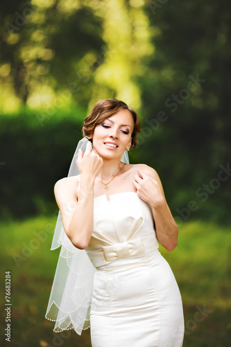 Adorable young caucasian bride in garden, sunny summer day.